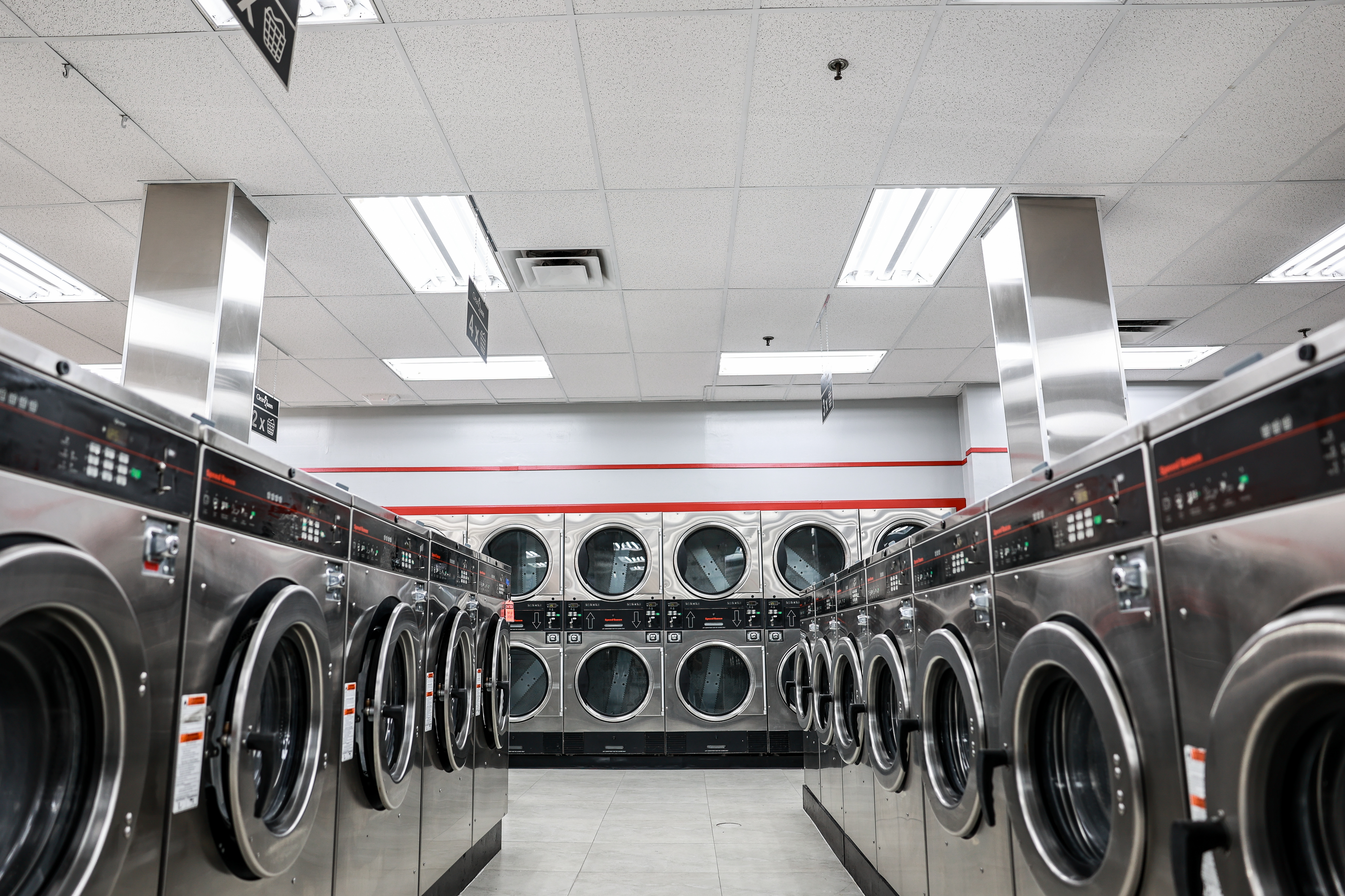Aisle of large-capacity washers and dryers at Clean Queen Laundry