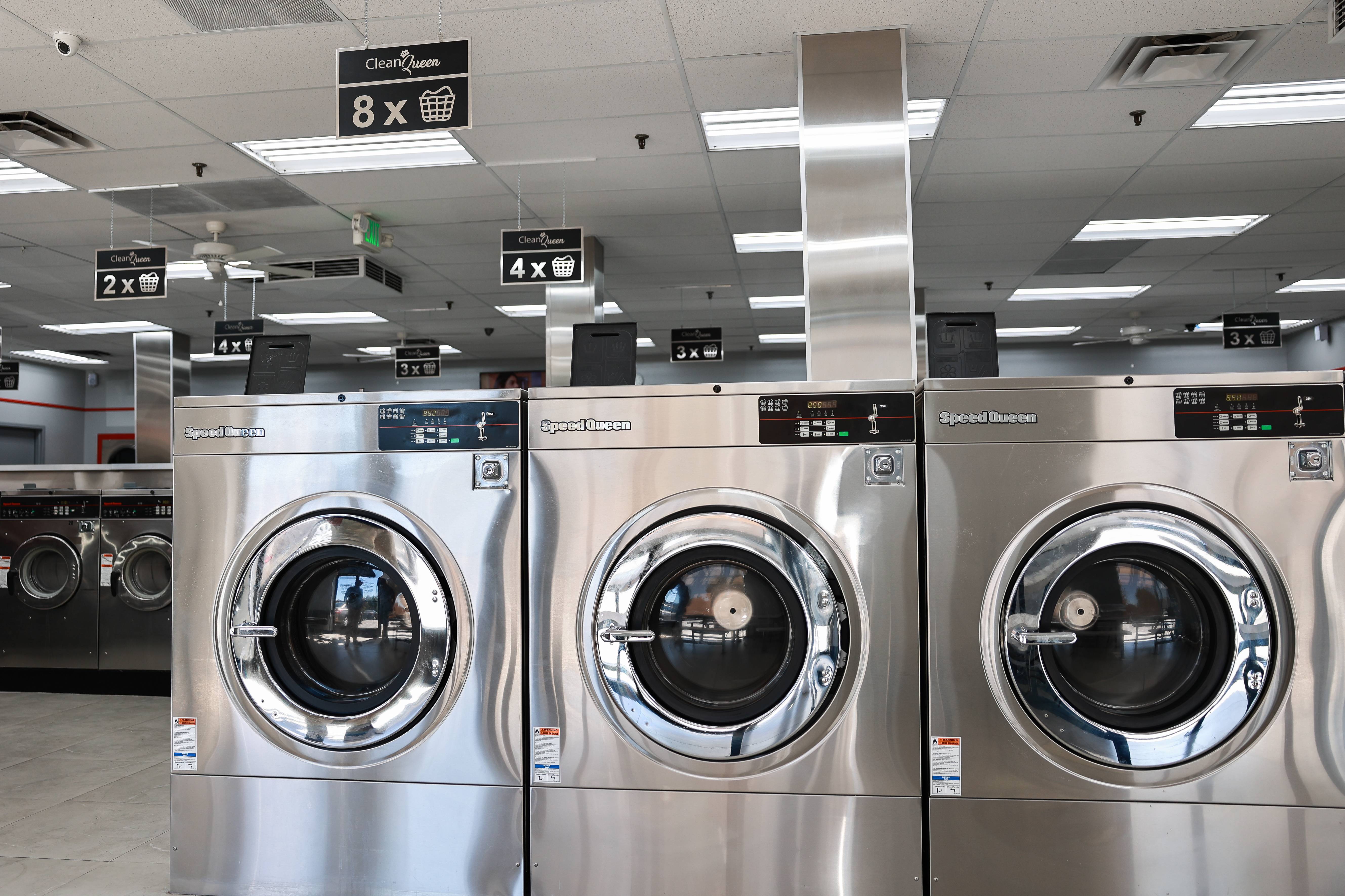 Row of stainless steel washers at Clean Queen Laundry
